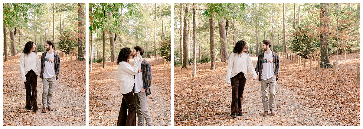 peyton-emma-walking-during-engagement-session.jpg Candid shot of Emma and Peyton walking holding hands down a wooded path, leaves underfoot, during their fall engagement session.
